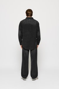 Black corduroy shirt with a slightly loose fit, long sleeves, and a round hem, paired with matching wide-leg trousers.