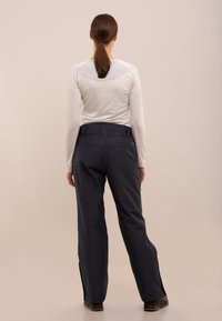 Tricou gri deschis cu mânecă lungă și pantaloni gri închis cu fermoare la glezne, fabricați dintr-un material durabil, concepuți pentru confort și mobilitate.