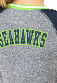 T-shirt en tissu gris avec "SEAHawks" en navy et un contour vert fluo, col rond avec accent vert, et manches raglan navy.