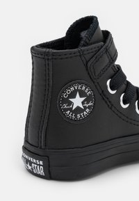 Czarne skórzane wysokie trampki Converse Chuck Taylor z białą naszywką w kształcie gwiazdy i czarną gumową podeszwą.