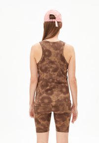 Bruin tie-dye tanktop en bijpassende shorts gemaakt van textuurstof. Het model draagt een lichtroze pet, gezien vanaf de achterkant.