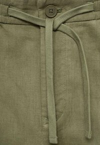 Pantalones verde oliva con cintura elástica, cierre de botón y tejido texturizado. Cuenta con bolsillos delanteros y detalles de costura distintivos.