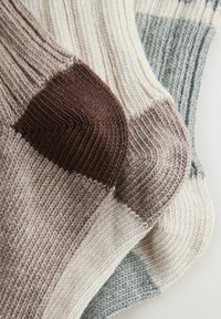 Pamutkeverékből készült kötött zoknik barna, bézs és világosszürke csíkokkal. Bordázott textúrájú, megerősített sarok- és lábujjrész.