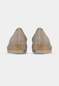 Beżowe zamszowe buty widziane od tyłu z korkowymi koturnami. Gładka faktura, zaokrąglone krawędzie i niskoprofilowy design z przeszytym szwem.