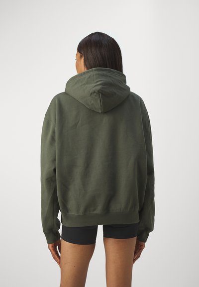 Felpa oversized verde oliva realizzata in morbido tessuto, con un ampio cappuccio, polsini a costine e una vita elasticizzata.