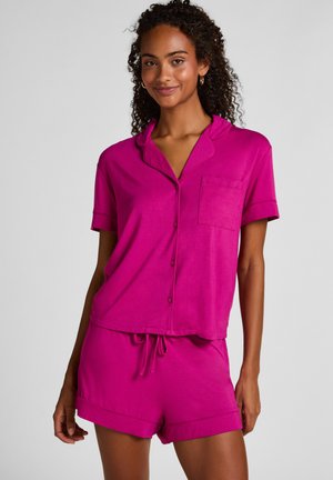 Roze korte mouwen pyjama set gemaakt van zachte stof, met een overhemd met knopen en een zak, en een korte broek met een tailleband met trekkoord.