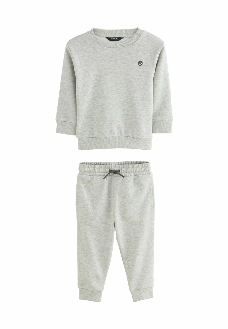 Sweat à manches longues gris clair avec des poignets côtelés, associé à un pantalon de jogging assorti avec une taille élastique et un cordon de serrage.