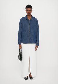 Denimshirt, pikad varrukad, nööbistamise ees, sinine värv. Valge maxi seelik ees lõhiku ja must käsikott ning korterkingad. Minimalistlik disain.