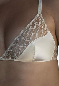 Kreemvärviline satiinist triangelrinnahoidja pits�äärisega, millel on lilleline tikand, pehme ja läbipaistev kangas ning õrnad õmblused äärel.