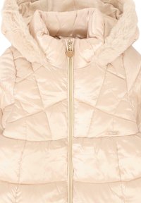 Chaqueta acolchada de un beige claro con capucha forrada de piel, patrón acolchado y detalles en dorado en la cremallera y la etiqueta del logo. Textura de tela suave y brillante.