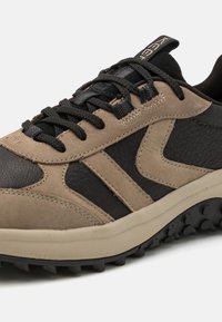 Herren Sneaker aus dunkelbraunem und schwarzem Leder mit beigen Akzenten, ausgestattet mit strukturierten Materialien, einer robusten Sohle und schwarzen Schnürsenkeln.