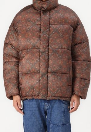 Dunjakke med høj krave, brunrødt mønstret stof, frontlommer, båret med blå denimjeans.