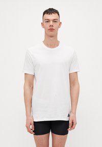 Λευκό κοντομάνικο T-shirt από βαμβάκι. Διαθέτει στρογγυλή λαιμόκοψη και μια μικρή μαύρη λογότυπη λεπτομέρεια στην κάτω αριστερή πλευρά. Ομαλή υφή.