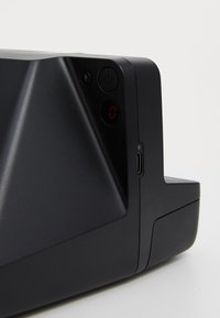 Black electronic device with a textured surface, featuring a power button, a charging port, and a digital display showing the number zero.