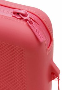 Custodia in silicone rosa con superficie texturizzata, chiusura con zip e una piccola maniglia. Presenta un design liscio e flessibile.