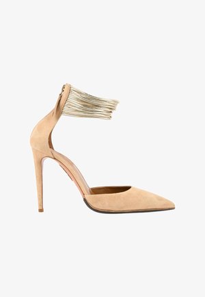 Chaussure à talon haut en daim beige avec bout pointu et bride de cheville métallique dorée avec fermeture éclair à l'arrière.