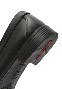 Scarpa in pelle nera con punta arrotondata, design a profilo basso, superficie testurizzata e suola in gomma con un accento rosso e battistrada pattern.