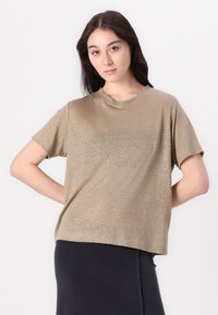 T-shirt z krótkim rękawem, luźny krój, wykonany z metalicznej beżowej tkaniny, z prostym okrągłym dekoltem i miękką, lekko teksturowaną powierzchnią.