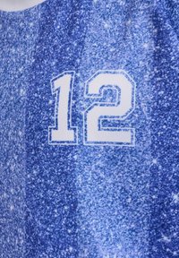 Hvidt tal "12" trykt på et blåt stof med et plettet mønster, der ligner stjerner eller en galaksetekstur.