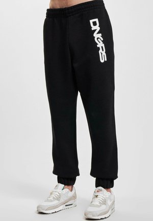 Pantaloni de trening negri cu o talie elastică, având un logo alb imprimat pe piciorul stâng și manșete ribbate la glezne.