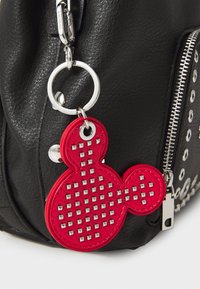 Borsa in pelle nera con zip argentata, dettagli a borchie e un charm a forma di Mickey Mouse rosso con borchie in metallo.