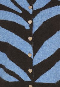 Cardigan lavorato a maglia con righe zigzag blu e nere, decorato con bottoni a forma di cuore dorati lungo il centro anteriore.