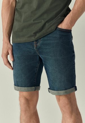 Mørkeblå denim shorts med lyseblå oprullede manchetter, der har fem lommer og orange syninger, lavet af et blødt og stærkt stof.