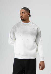 Witte sweatshirt met een verloop in grijstinten, versierd met kleine zwarte accenten. Losse pasvorm en geribbelde boorden bij de polsen en zoom.
