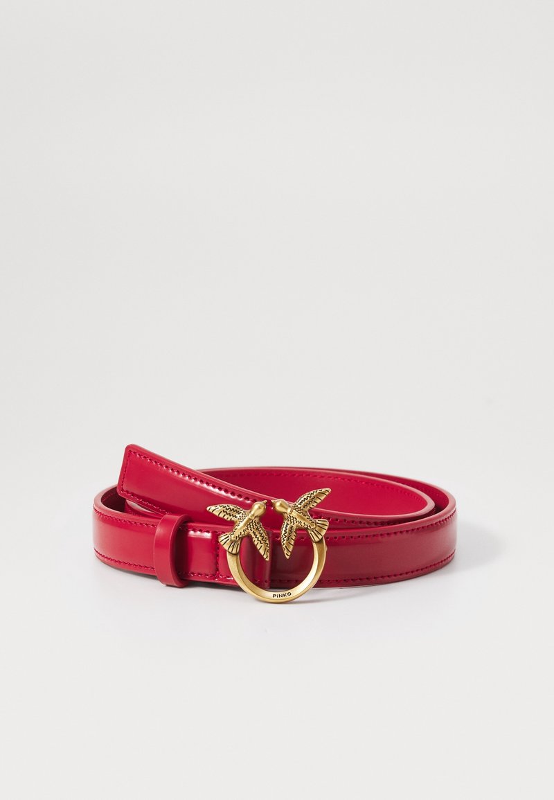 Ceinture en cuir rouge enroulée avec une boucle dorée ornée de deux oiseaux détaillés se faisant face.