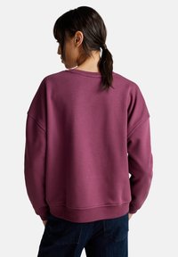 Overmaat, pullover sweatshirt in een diep bordeauxrood stof. Heeft een ronde halslijn, ribgebreide boorden en een relaxte pasvorm met verlaagde schouders.