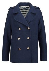 Manteau caban bleu marine à double boutonnage avec six boutons dorés, larges revers, épaulettes et doublure intérieure rayée.