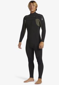 Čierny neoprenový oblek so zelenými akcentmi, dlhými rukávmi a priliehavým strihom. Obsahuje spevnené kolenné panely a zips na krku. Hladká textúra a flexibilný materiál.