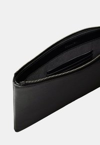 Pochette en cuir noir avec une finition texturée, dotée d'une fermeture éclair sur le dessus et d'un compartiment pour cartes à l'intérieur. Design simple et rectangulaire.