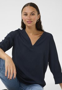 Blusa blu navy, decorata con texture, con scollatura a V e maniche a tre quarti, caratterizzata da pieghe sottili e una vestibilità rilassata.
