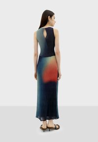 Mouwloze, lange jurk met een gradient patroon van marineblauw naar oranje, met een sleutelgatdetail op de rug en een textuurstof.