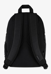 Črn nahrbtnik z teksturirano tkanino, podloženimi prilagodljivimi naramnicami in zgornjim ročajem. Ima mrežasto stransko žepko in minimalno blagovno znamko.