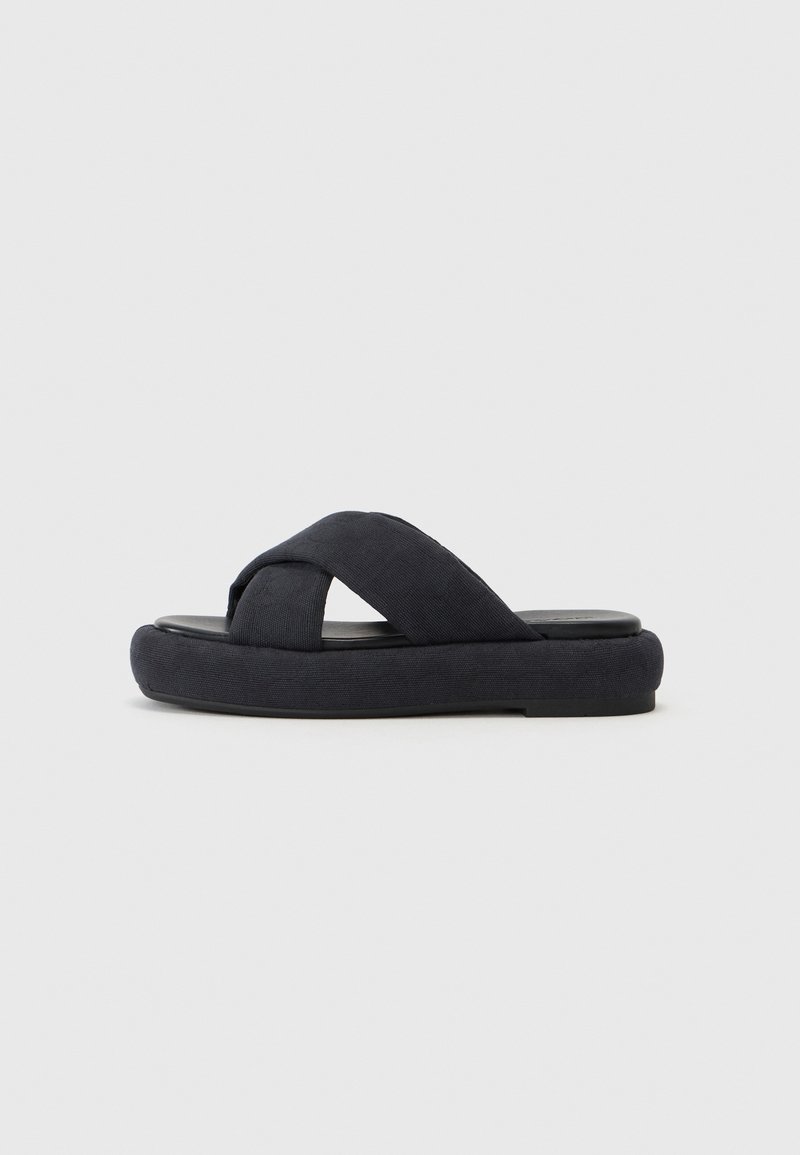 Marineblå slip-on sandal med kryssbrodert stoffoverdel, polstret såle og glatt kontrastfarget svart fotbed. Minimalistisk design.