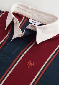 Koszulka polo z kołnierzykiem w paski w kolorze burgundowym, granatowym i kremowym. Posiada haftowane logo oraz żebrowany kołnierz. Wykonana z miękkiej bawełny.