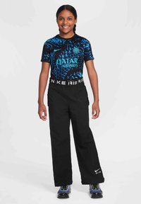 Czarne sportowe spodnie o szerokim kroju, połączone z koszulą z krótkim rękawem w niebiesko-czarne wzory z logo "Qatar Airways" i "Nike".