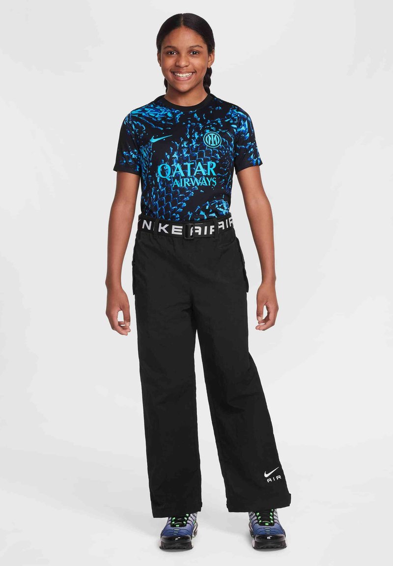 Czarne sportowe spodnie o szerokim kroju, połączone z koszulą z krótkim rękawem w niebiesko-czarne wzory z logo "Qatar Airways" i "Nike".