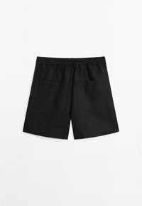 Shorts en lin noir avec taille élastique et deux grandes poches arrière présentés sur fond blanc.