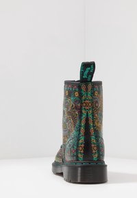 Botín negro con patrones coloridos de flores y calaveras, textura suave, suela resistente y una pestaña para facilitar su colocación.