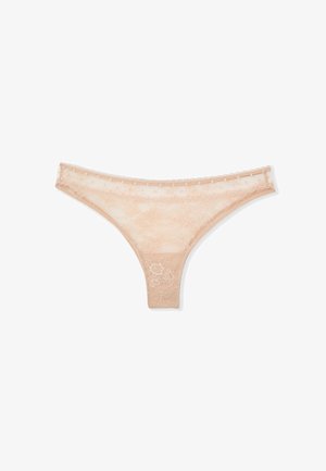Beige Spitzen-String mit floralem Muster und wellenförmigen Kanten vor weißem Hintergrund.