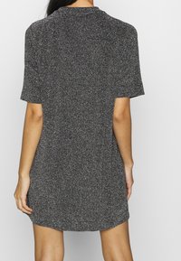 Vestido de manga corta en tejido negro con manchas plateadas, con un ajuste relajado y un escote redondo, con una textura suave y un corte a la altura de la rodilla.