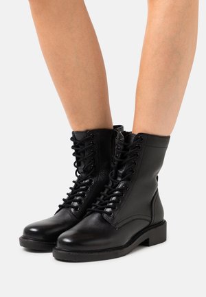 Botines de piel negra con puntera redonda, cierre de cordones, superficie texturizada y tacón bajo en bloque.