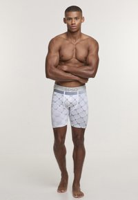 Men's boxer briefs in white with a geometric black pattern. Features a gray elastic waistband with "PSD" logo. Smooth, stretchy fabric.