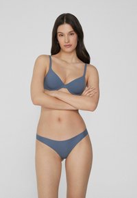 Grauer gepolsterter BH mit verstellbaren Trägern, kombiniert mit passenden nahtlosen Bikini-Höschen. Glatte Textur, minimales Design und konturierte Form.
