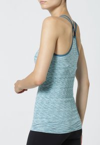 Jasnoniebieski sportowy top na ramiączkach z teksturowanym wzorem i cienkimi paskami. Posiada zaokrąglony dekolt i dopasowany krój.
