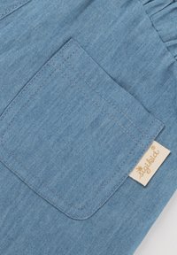 Blue fabric featuring a diamond-shaped pocket with contrasting stitching and a cream tag labeled "sigikid®" visible on the side.