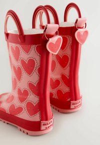 Rote wasserdichte Gummistiefel mit rosa Herzmuster, zwei Griffen, strukturierten Sohlen und einem "HELLO LOVE"-Etikett auf der Rückseite.